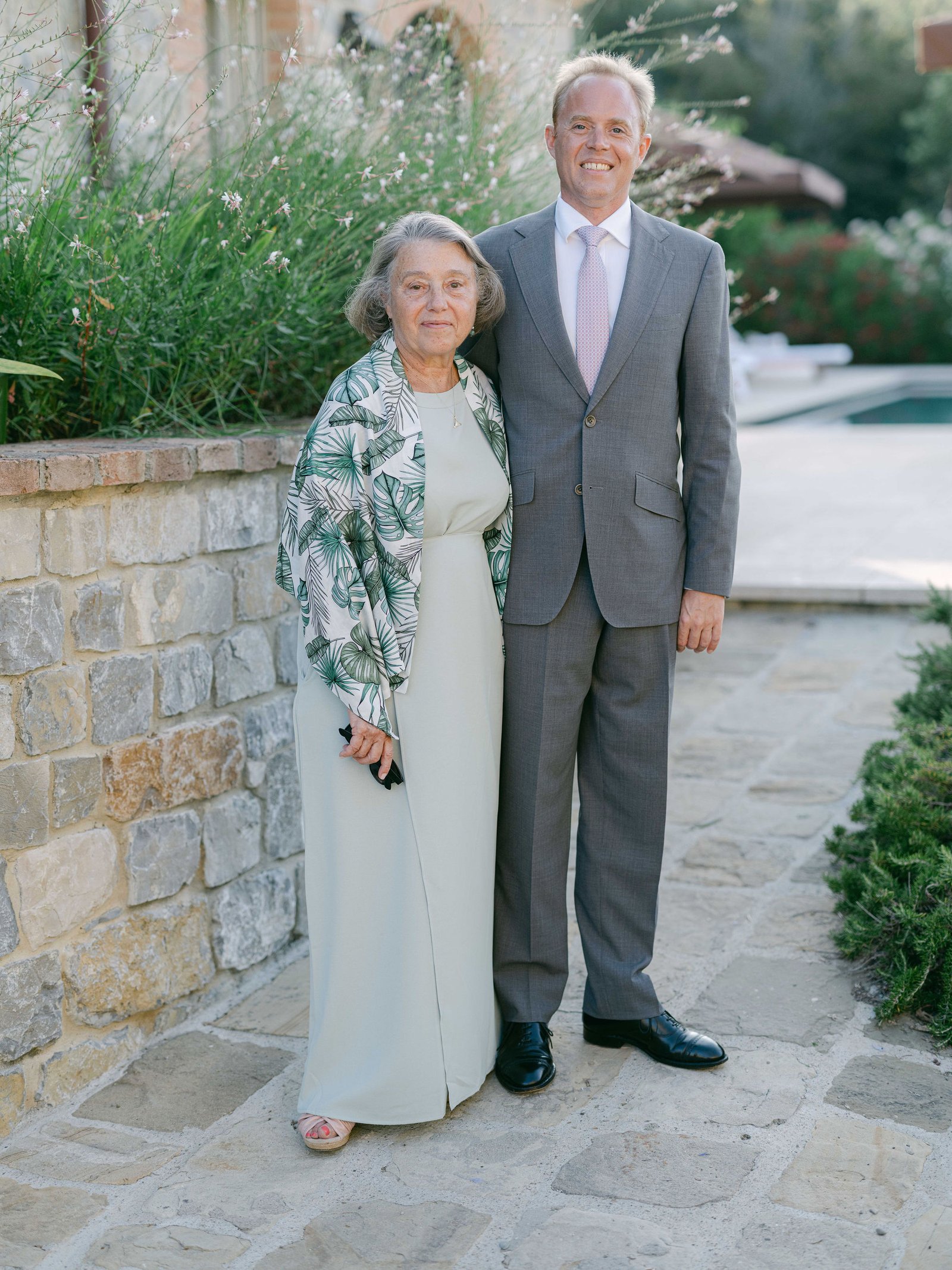 Family formals portrait of wedding parents on Tuscan stone terrace at Castiglione del Bosco in soft evening light