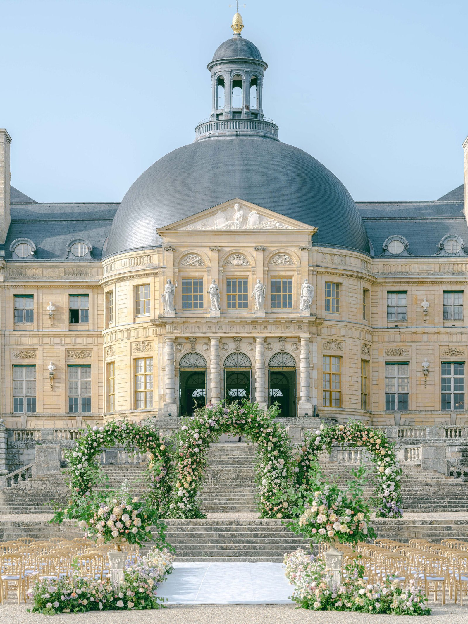 Vaux-le-Vicomte ceremony setup, floral arches in the Dome Ovale at golden hour