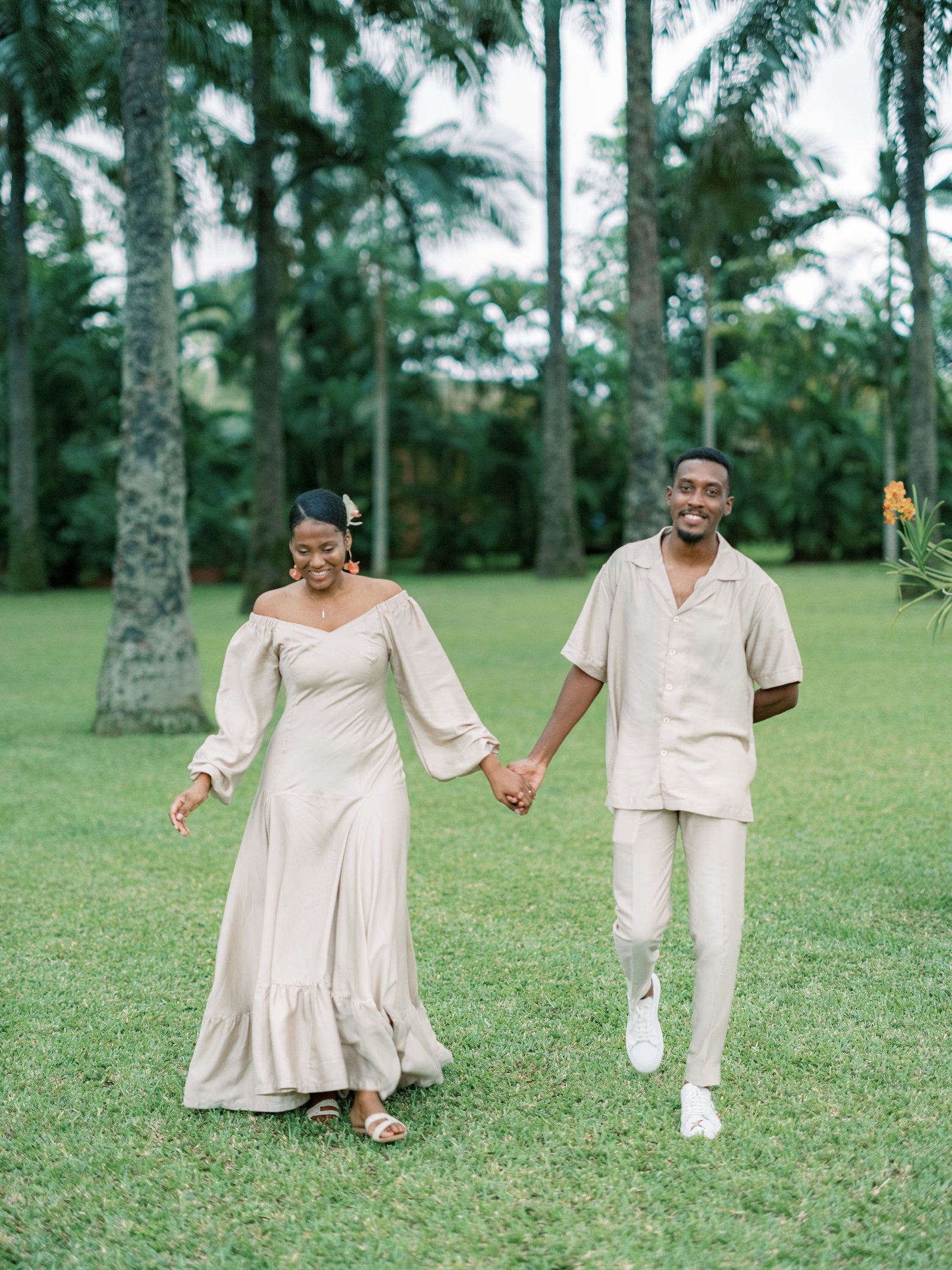 Couple walking hand in hand through a tropical garden at an Abidjan villa in soft evening light