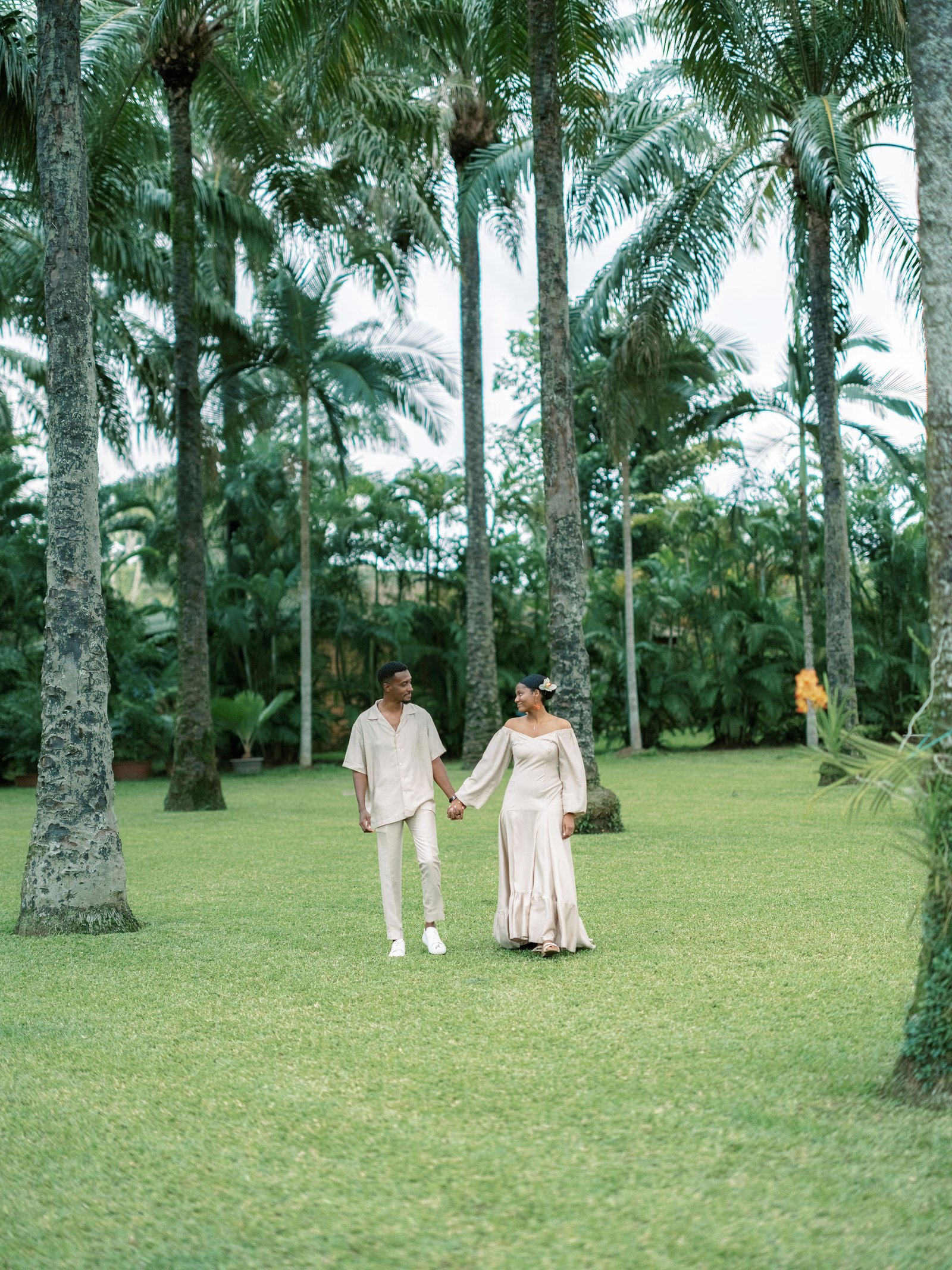 Couple walking together through tropical palm gardens in Abidjan in soft evening light