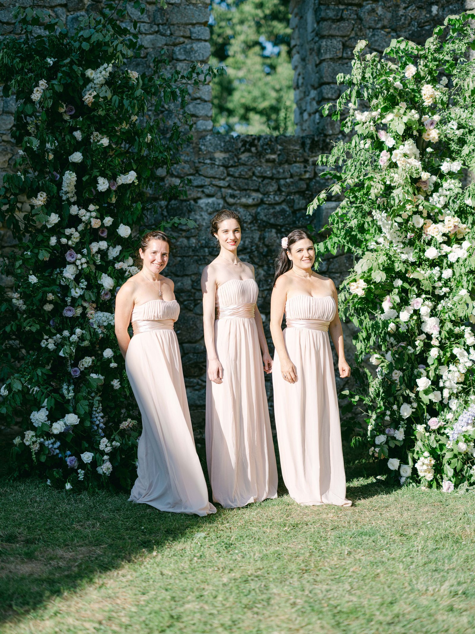 Family formals bridesmaids by stone wall and rose garden at Chateau de Luzeret in soft evening light