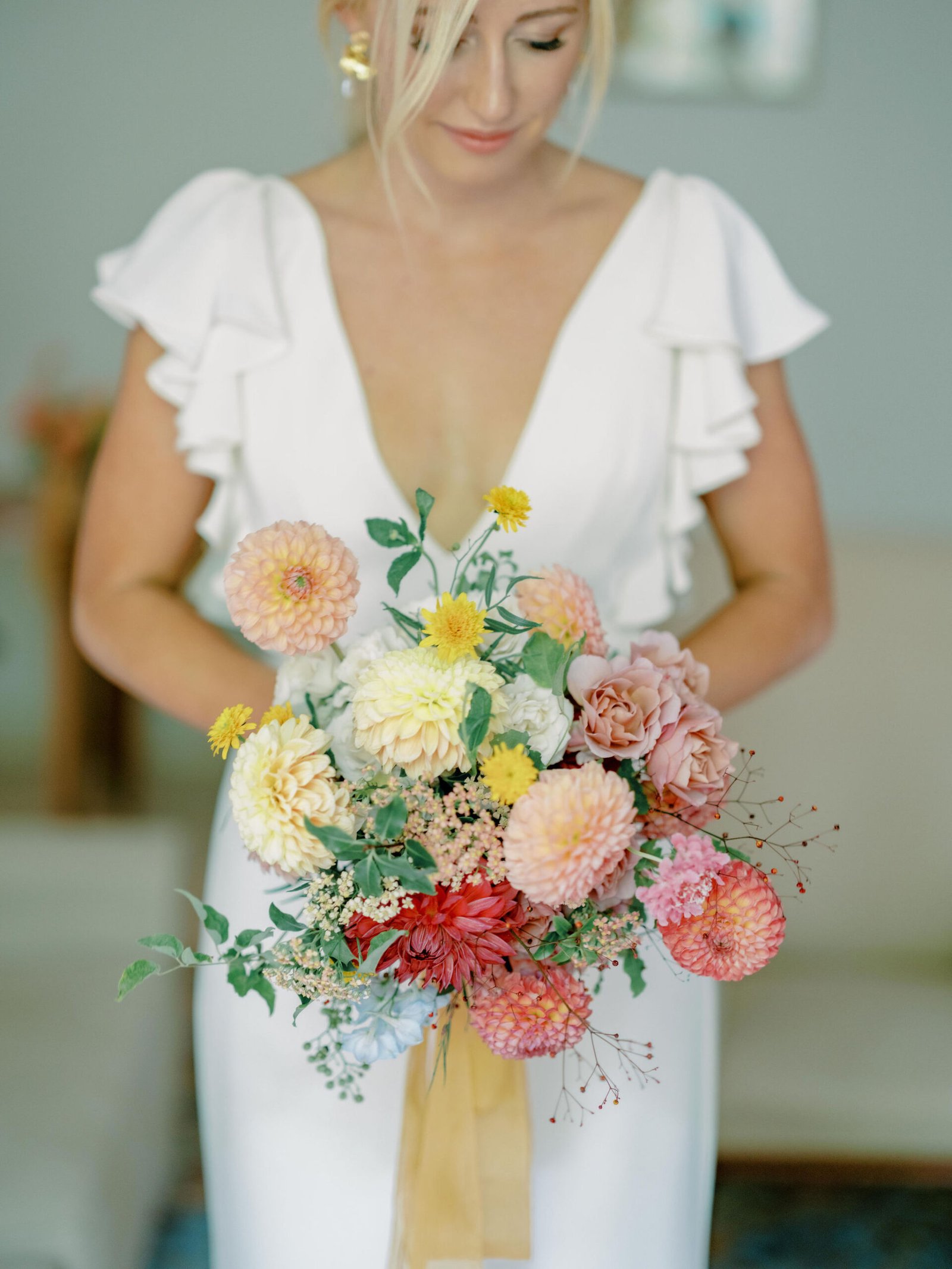 Bride holding dahlia bouquet in flutter sleeve gown during golden hour at Chateau Sainte Roseline