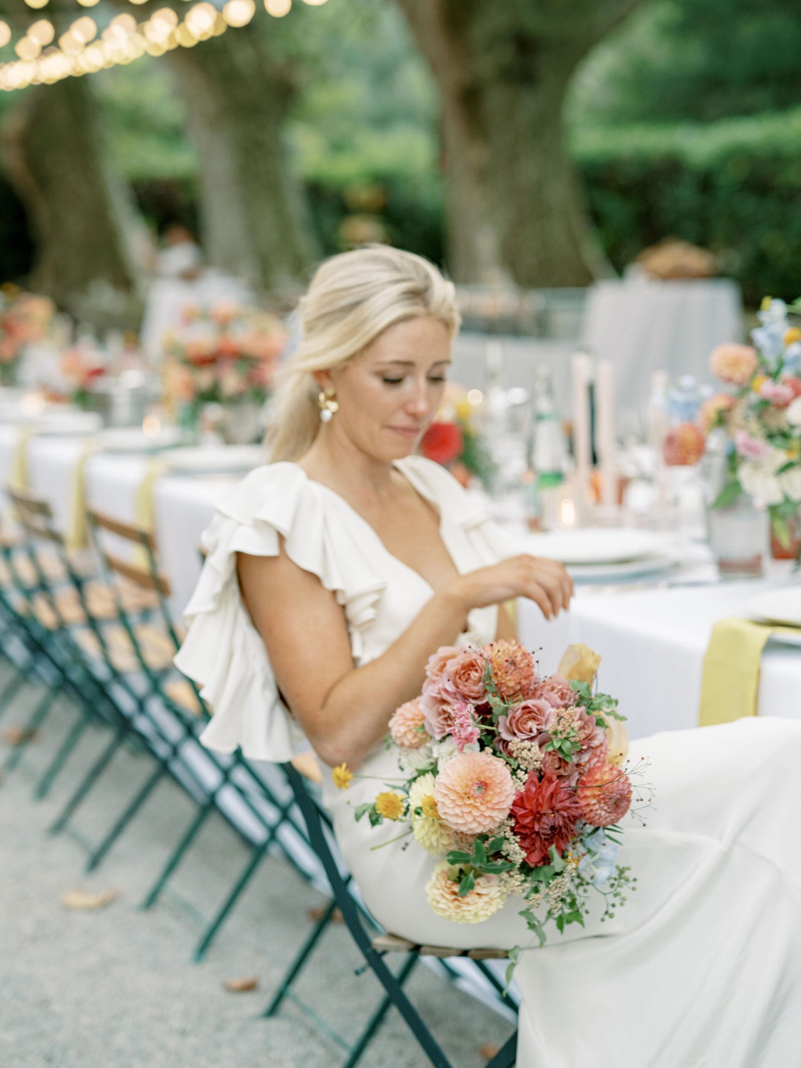 Bride with dahlia bouquet during reception under fairy lights at Chateau Sainte Roseline in Provence