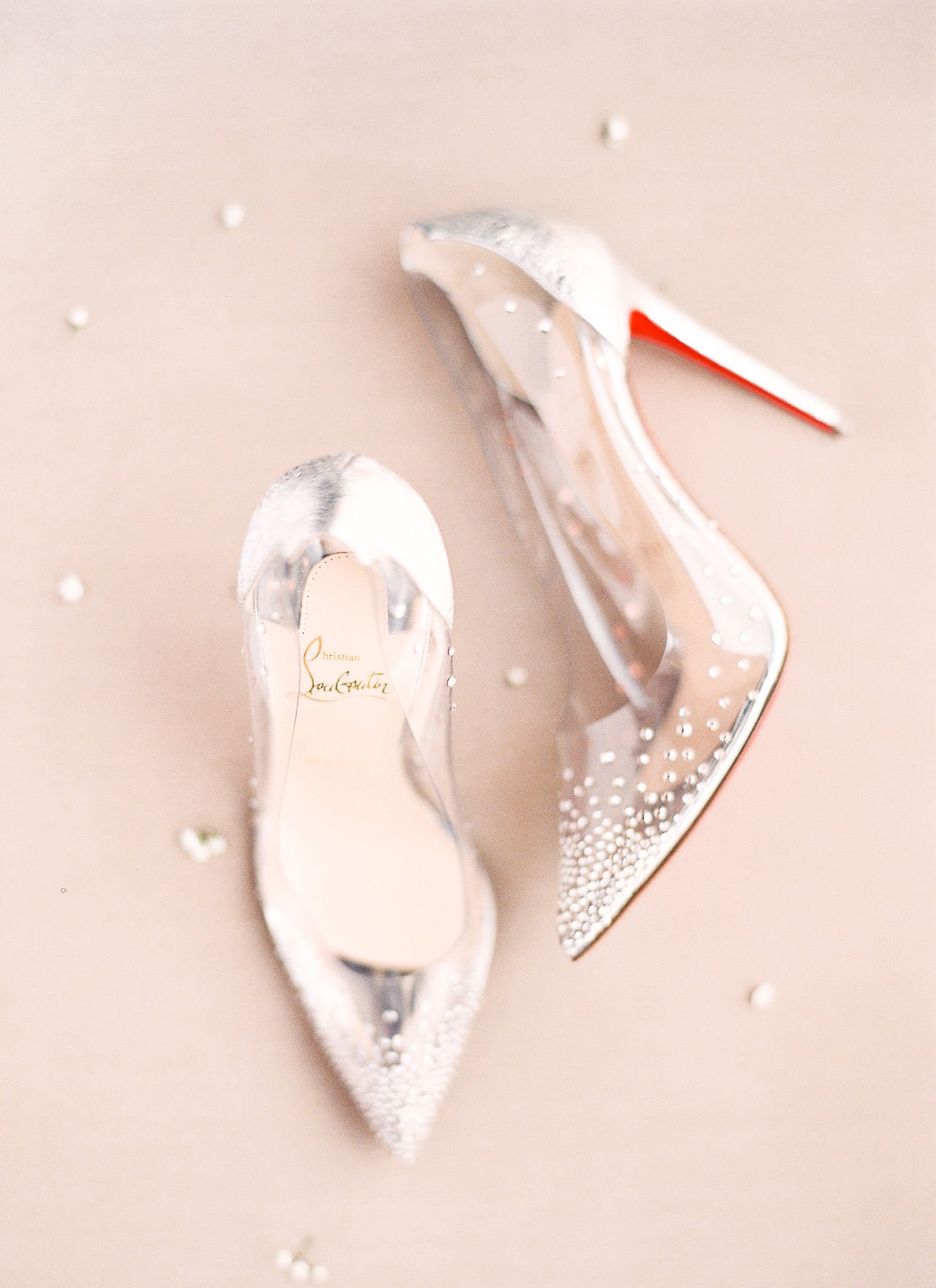 Christian Louboutin bridal heels with crystal embellishments and signature red soles on blush backdrop
