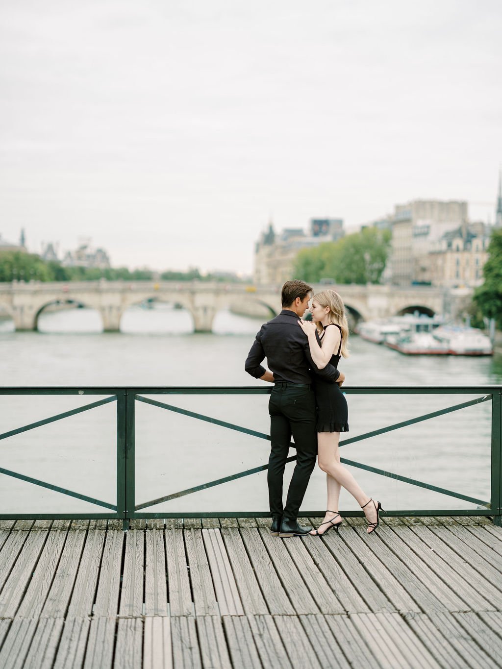 Intimate couple portrait on Pont des Arts with Pont Neuf and the Seine River in the background