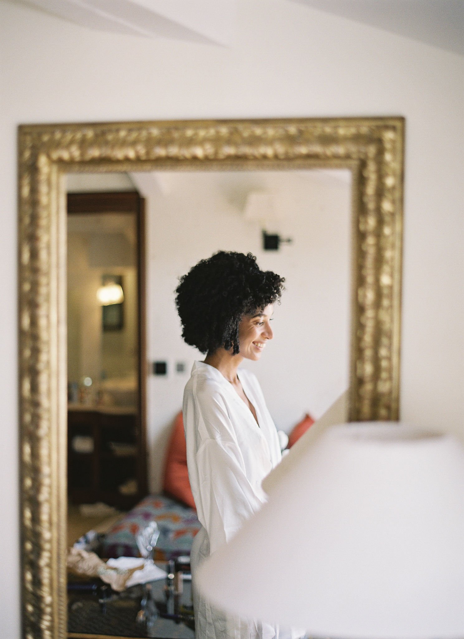 Bride in silk robe smiling during getting ready preparations at Pan Deï Palais Saint-Tropez in golden light