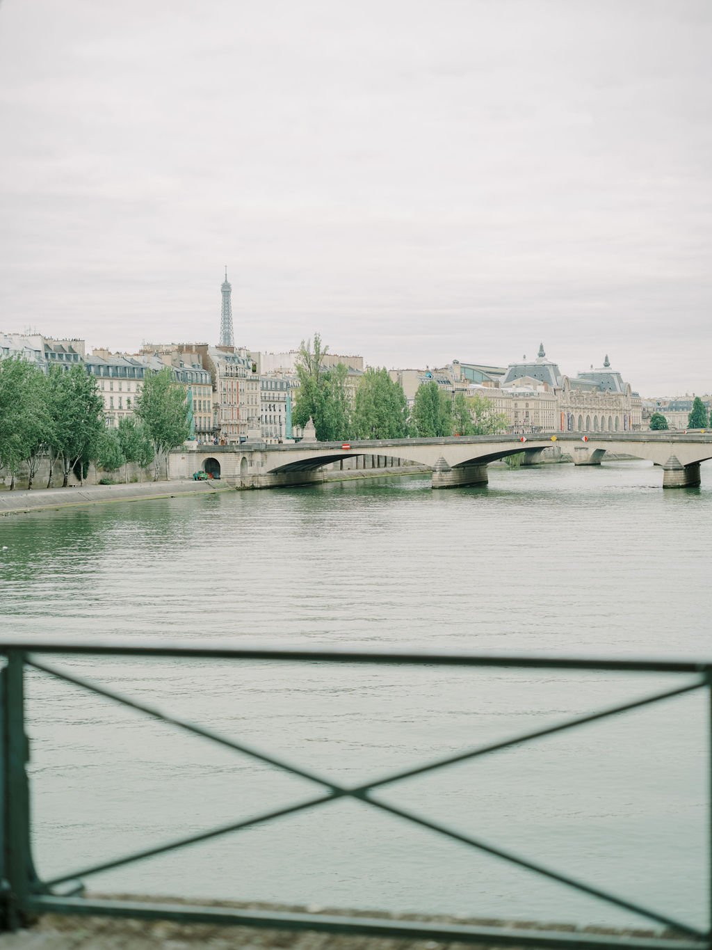 Paris engagement session along the Seine with Eiffel Tower in view, couple walking in soft overcast morning light