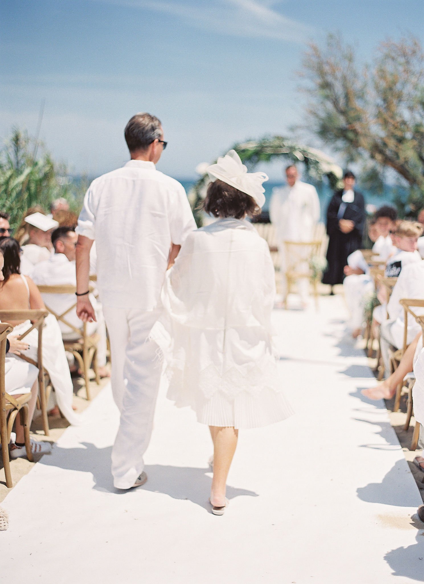 Couple walking down wedding aisle in white linen at luxurious Saint-Tropez ceremony in golden afternoon light