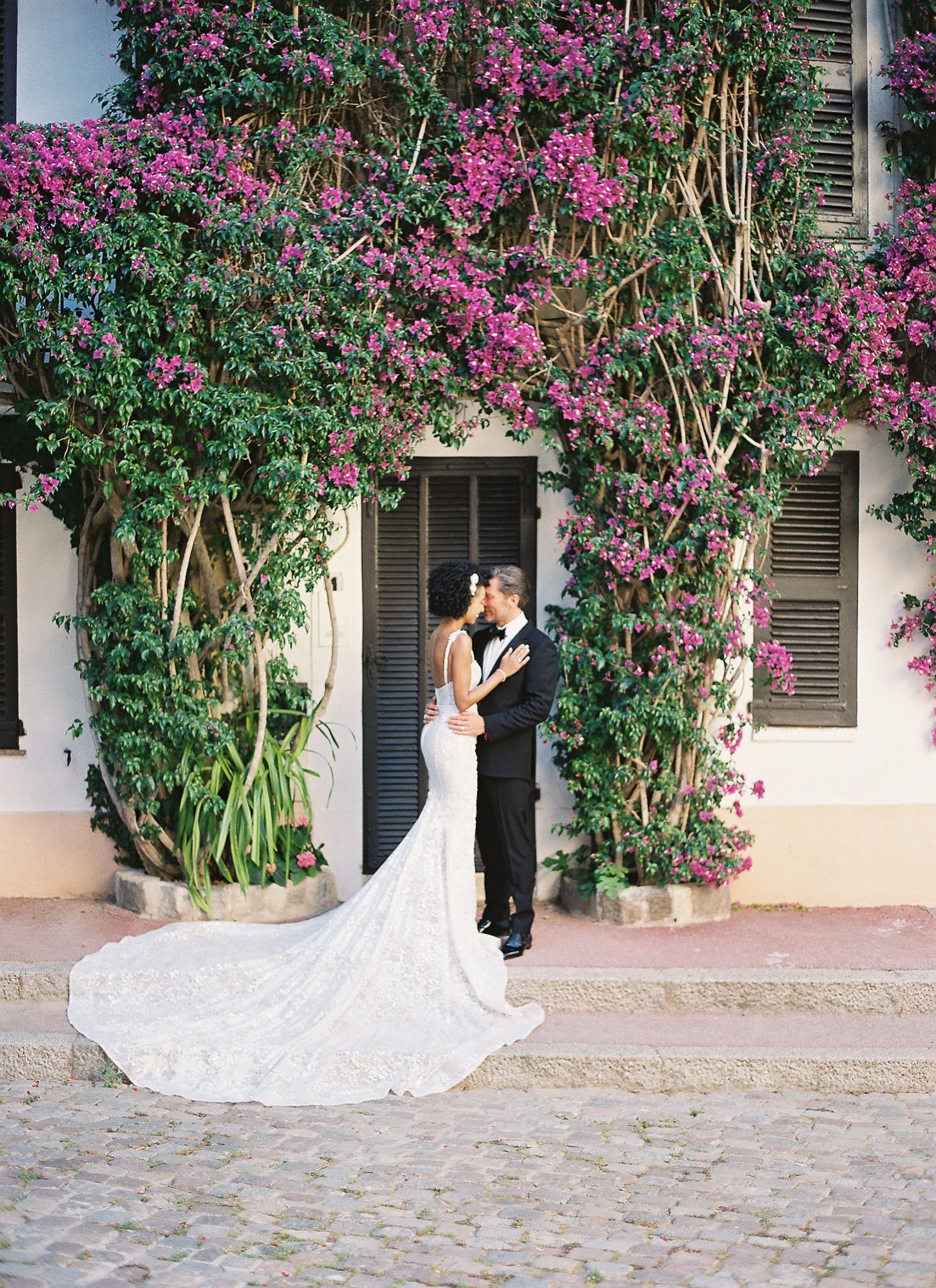Bride and groom embracing in golden hour light beneath vibrant bougainvillea at Saint-Tropez luxury hotel courtyard