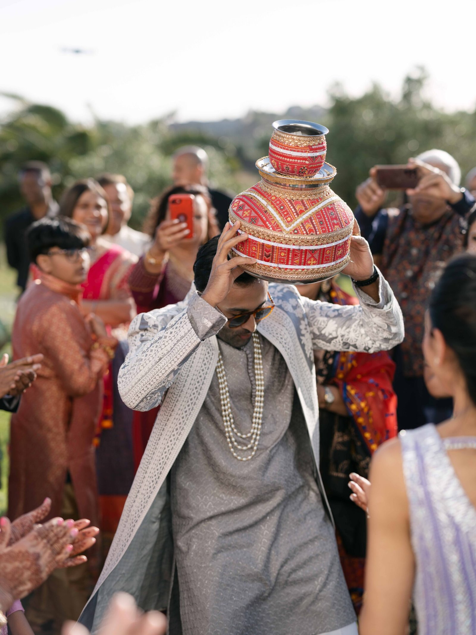 Groom performing a traditional pot ritual as guests celebrate at an Indian wedding ceremony in Lisbon