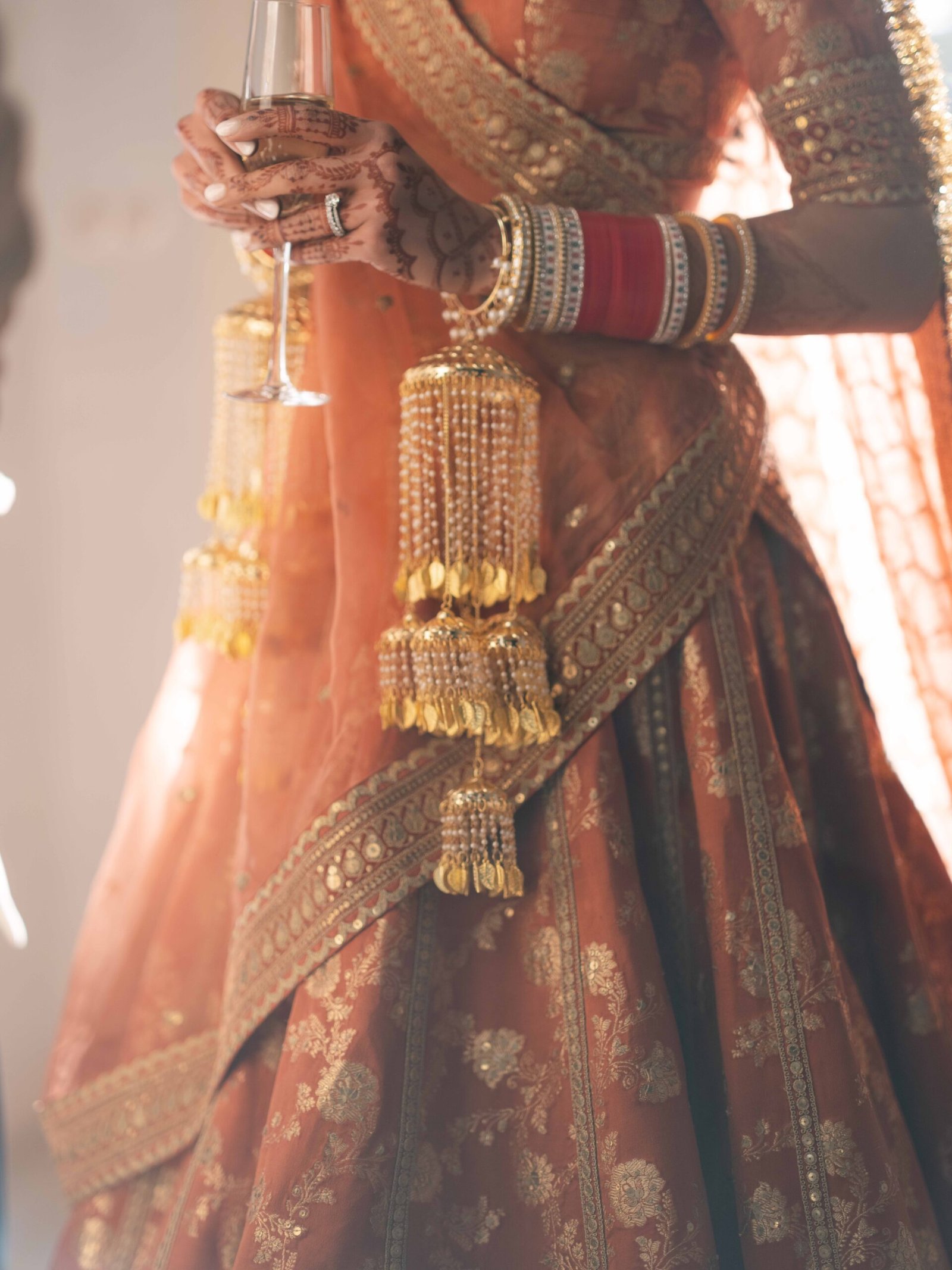 Bride's hands with kaleere and mehndi holding a glass of champagne, Indian wedding in Lisbon