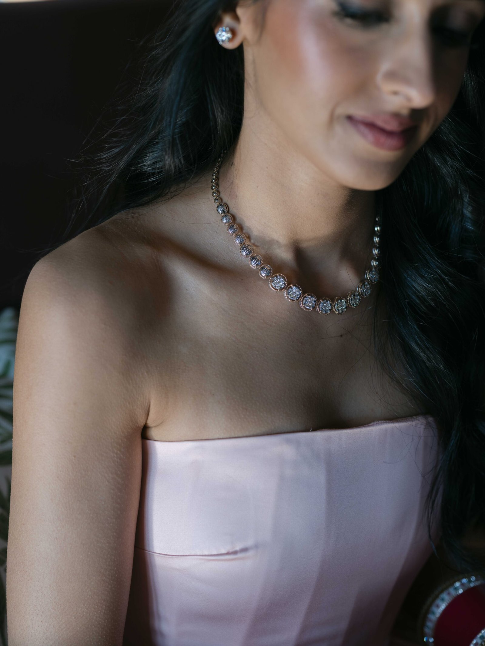 Bride wearing a diamond necklace and blush gown while getting ready for her Lisbon wedding