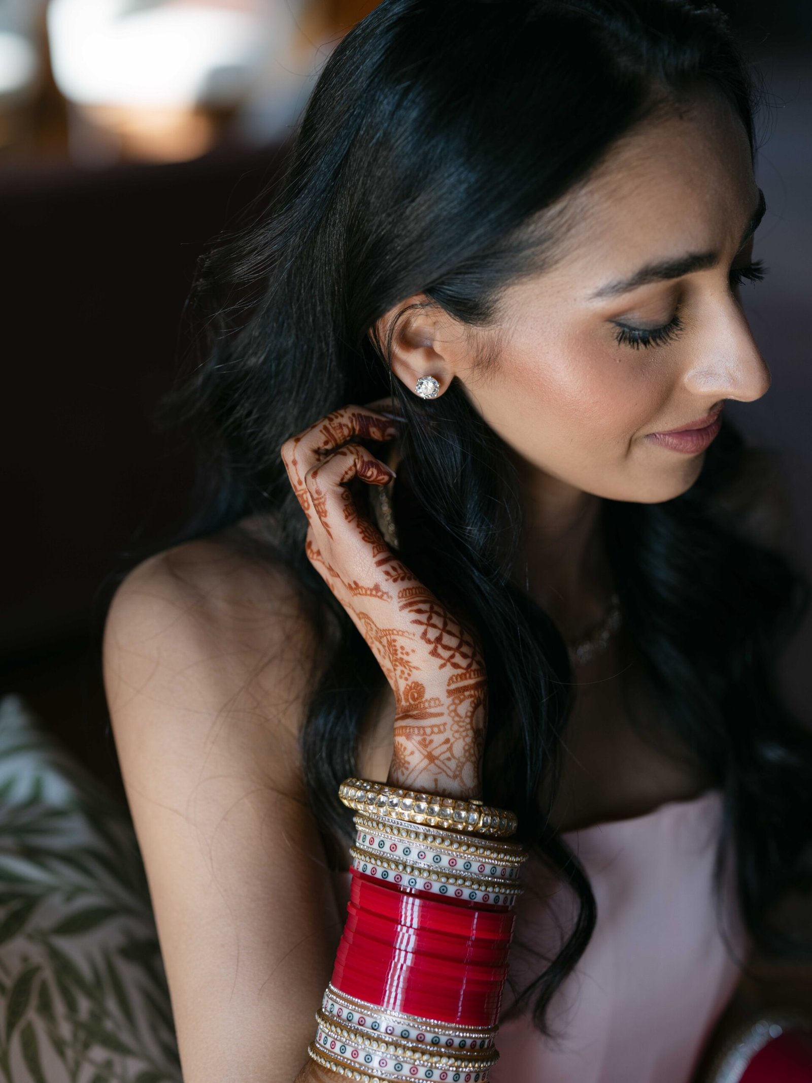 Close-up of an Indian bride's henna, bangles and diamond earring in soft window light, Lisbon