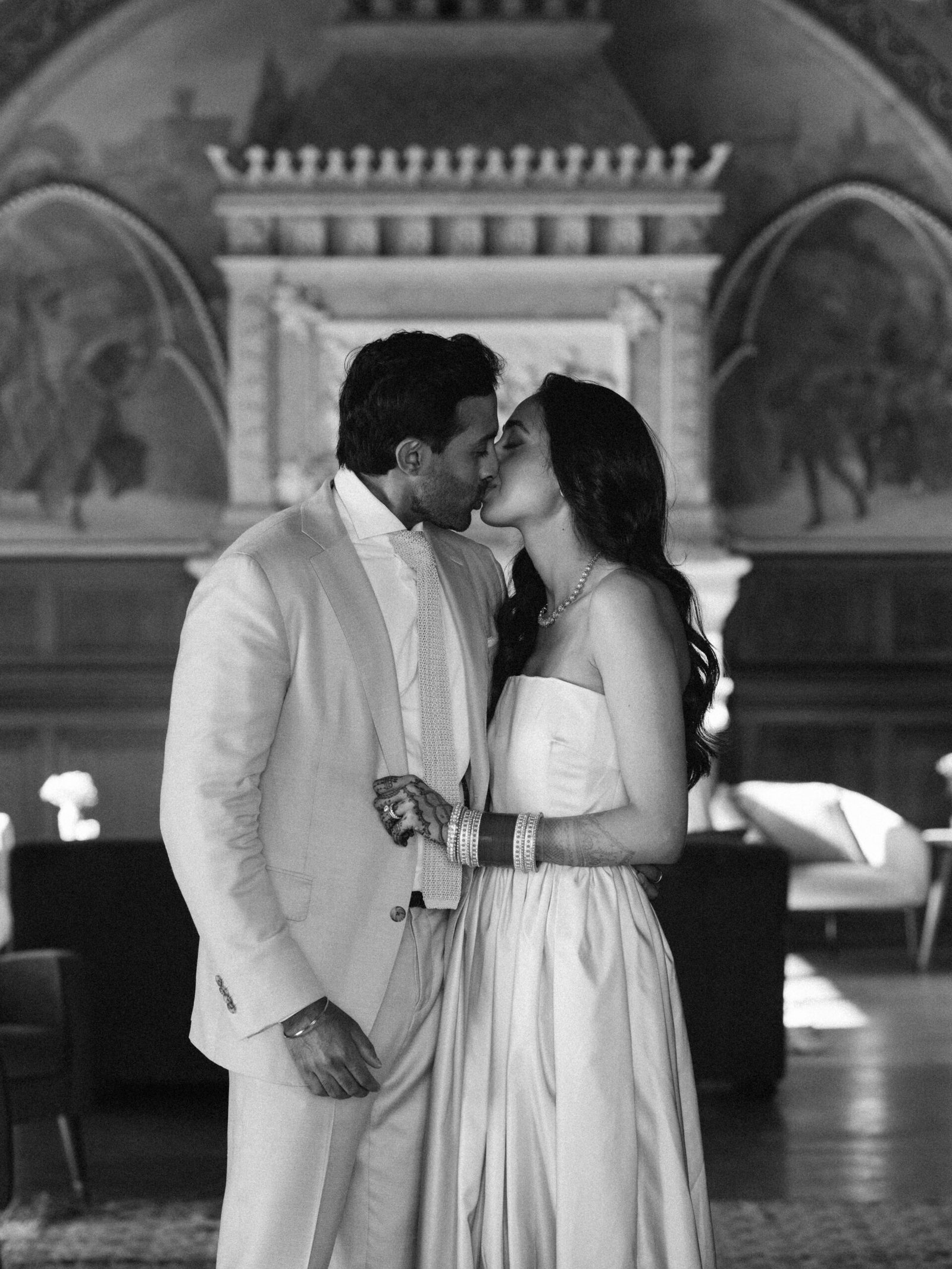 Bride and groom kissing in a frescoed palace hall after their ceremony in Lisbon