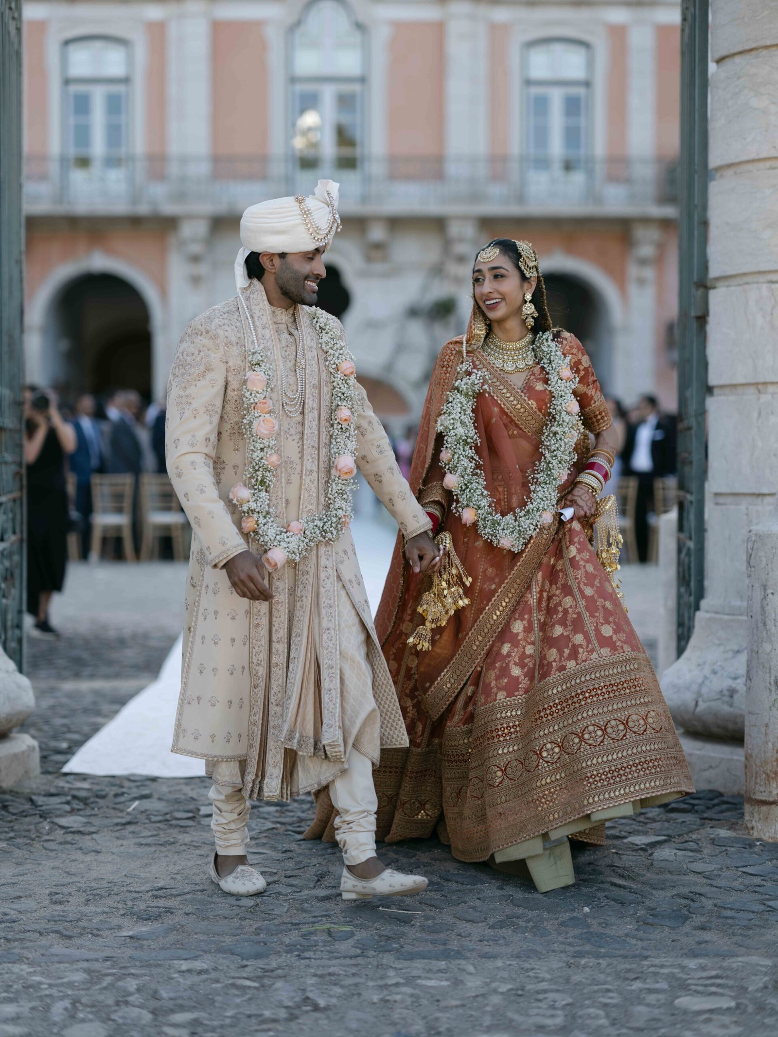 Indian couple wearing floral garlands in a palace courtyard in Lisbon at golden hour