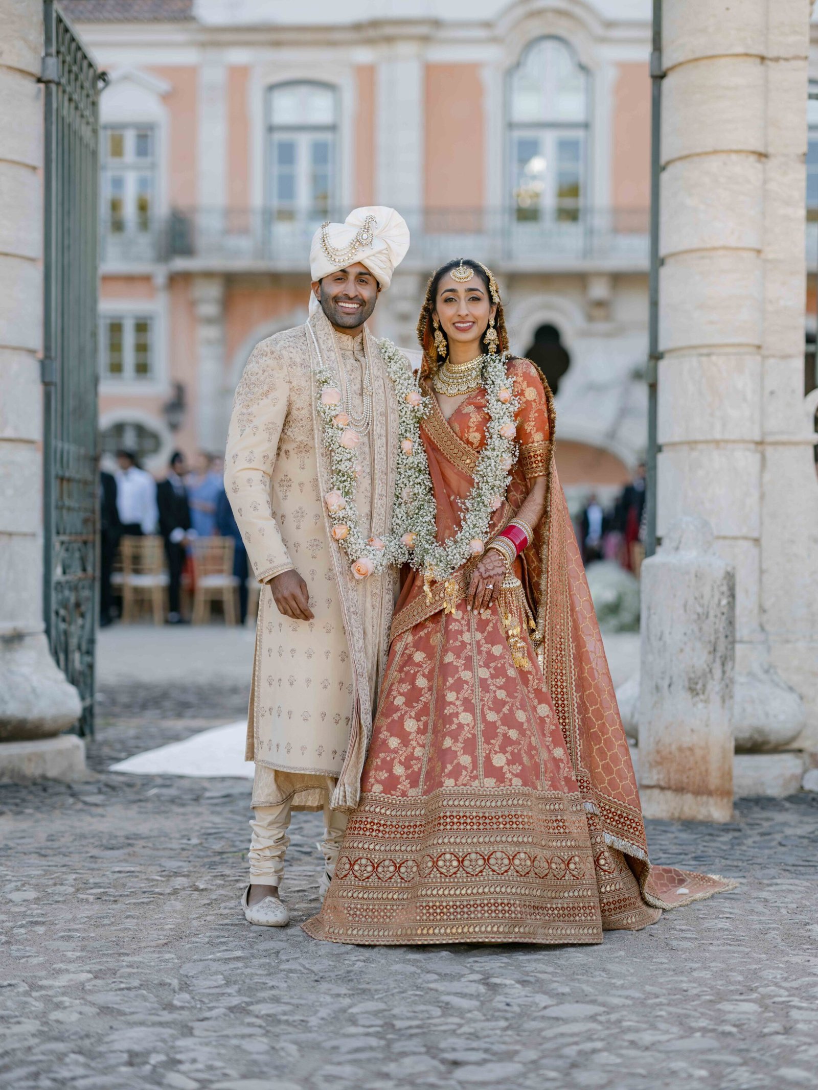 Indian couple in traditional attire with jasmine garlands in a Lisbon palace, soft evening light