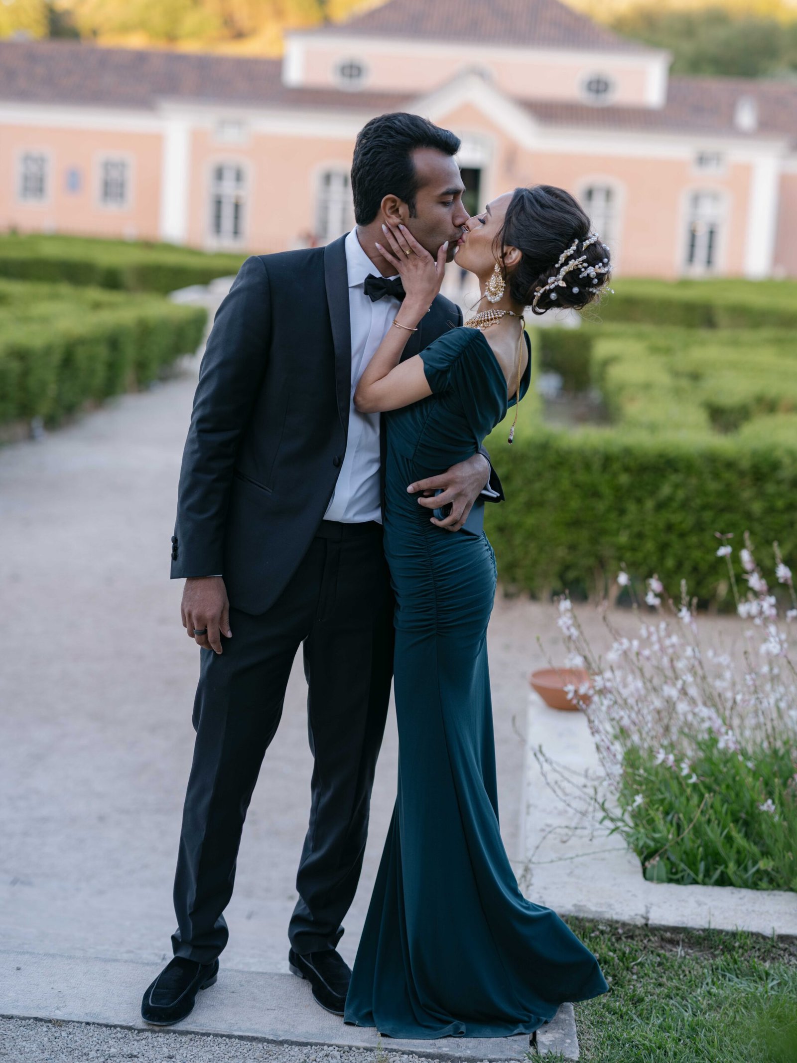 Couple kissing in a garden, the bride in an emerald gown, golden hour in Lisbon