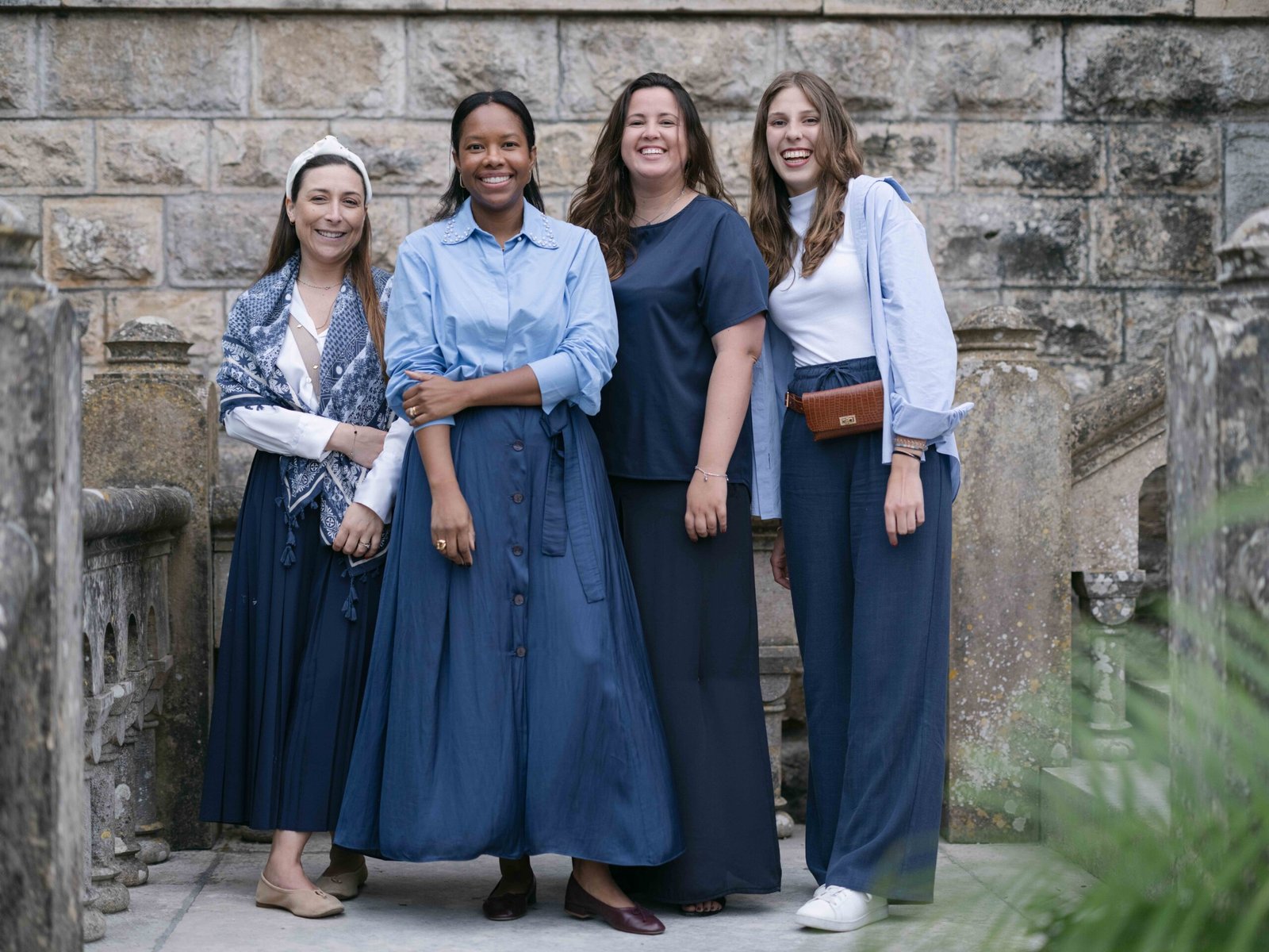Wedding guests in blue attire by a stone balustrade in Lisbon, soft evening light