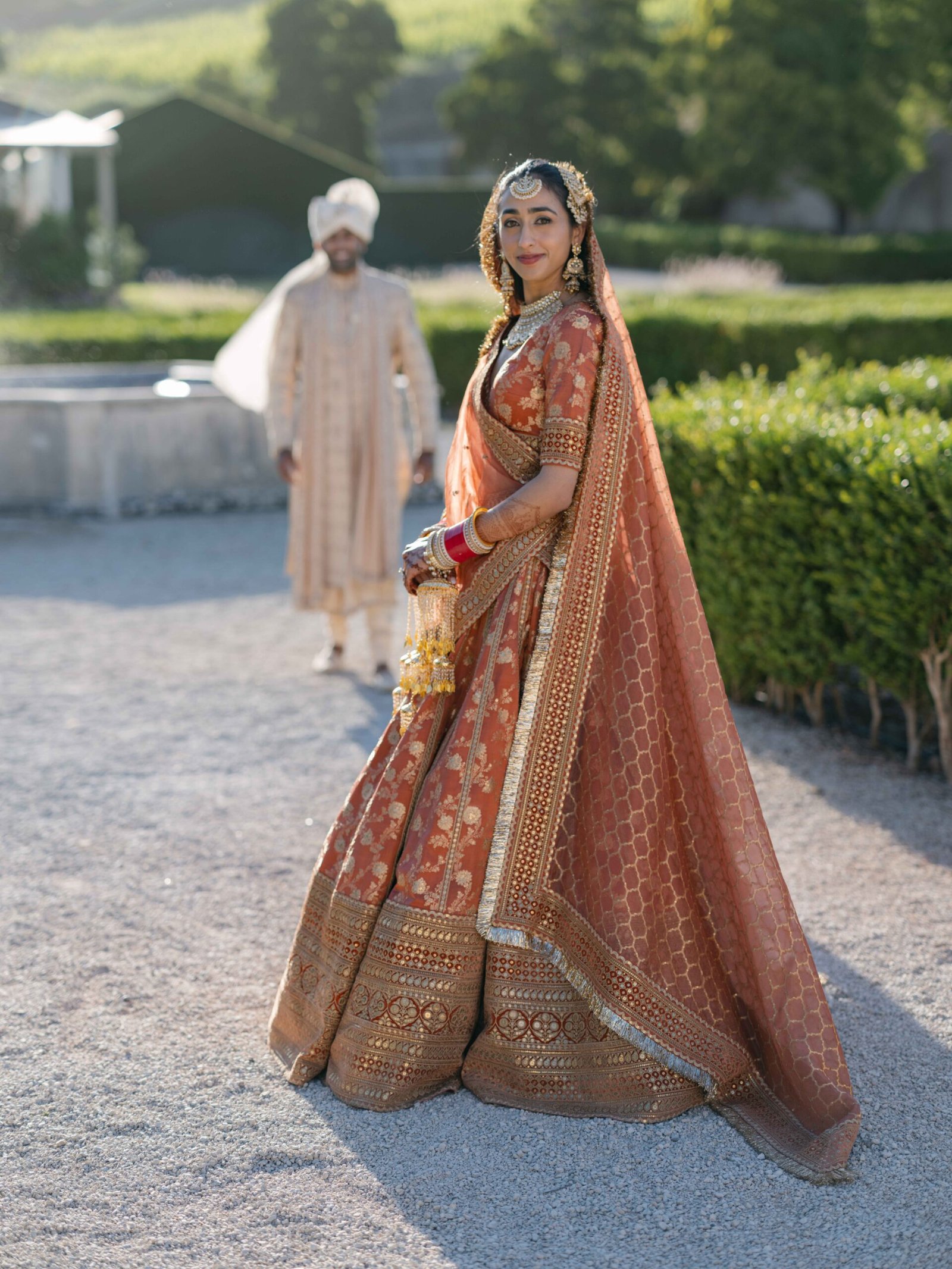 Indian bride in a rust lehenga in a garden in Lisbon at golden hour