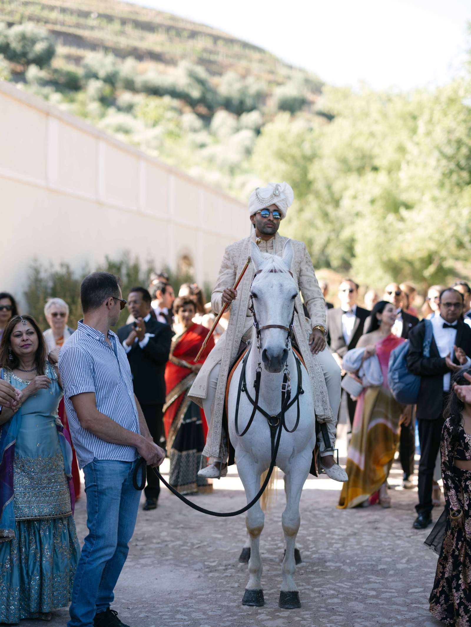 Groom arriving on a white horse in sherwani and turban for the baraat in Lisbon, golden hour