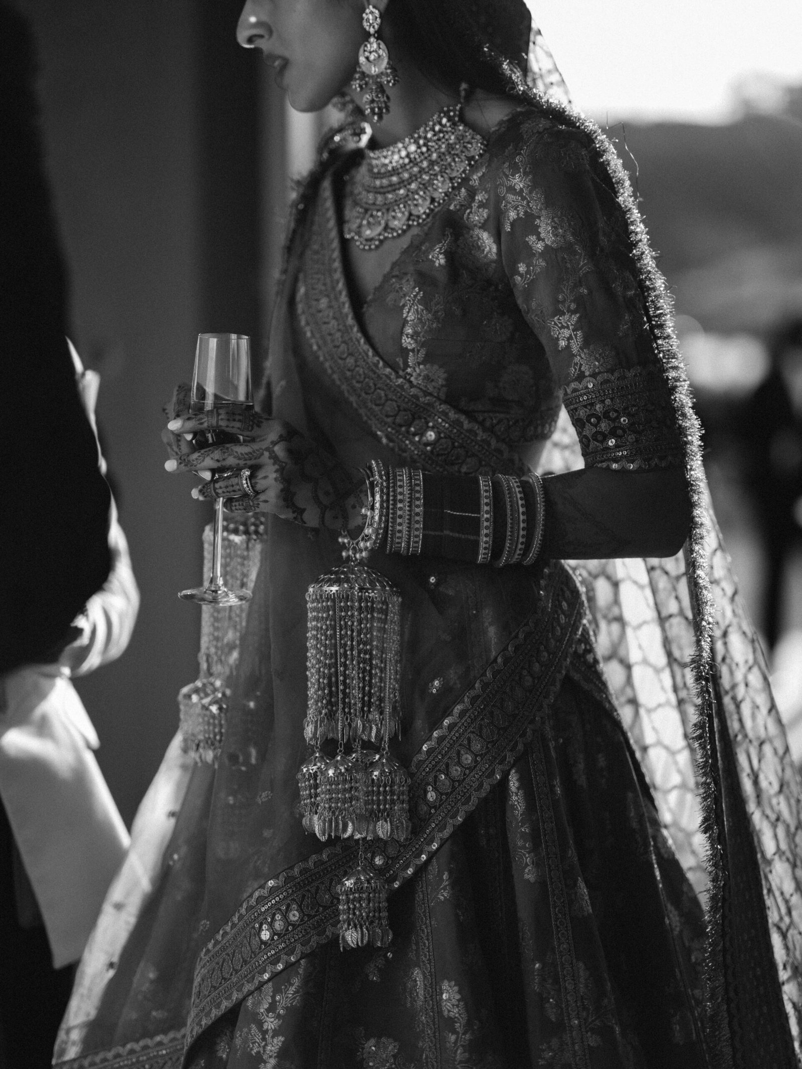 Indian bride in a bridal lehenga with mehndi holding champagne at the evening cocktail in Lisbon