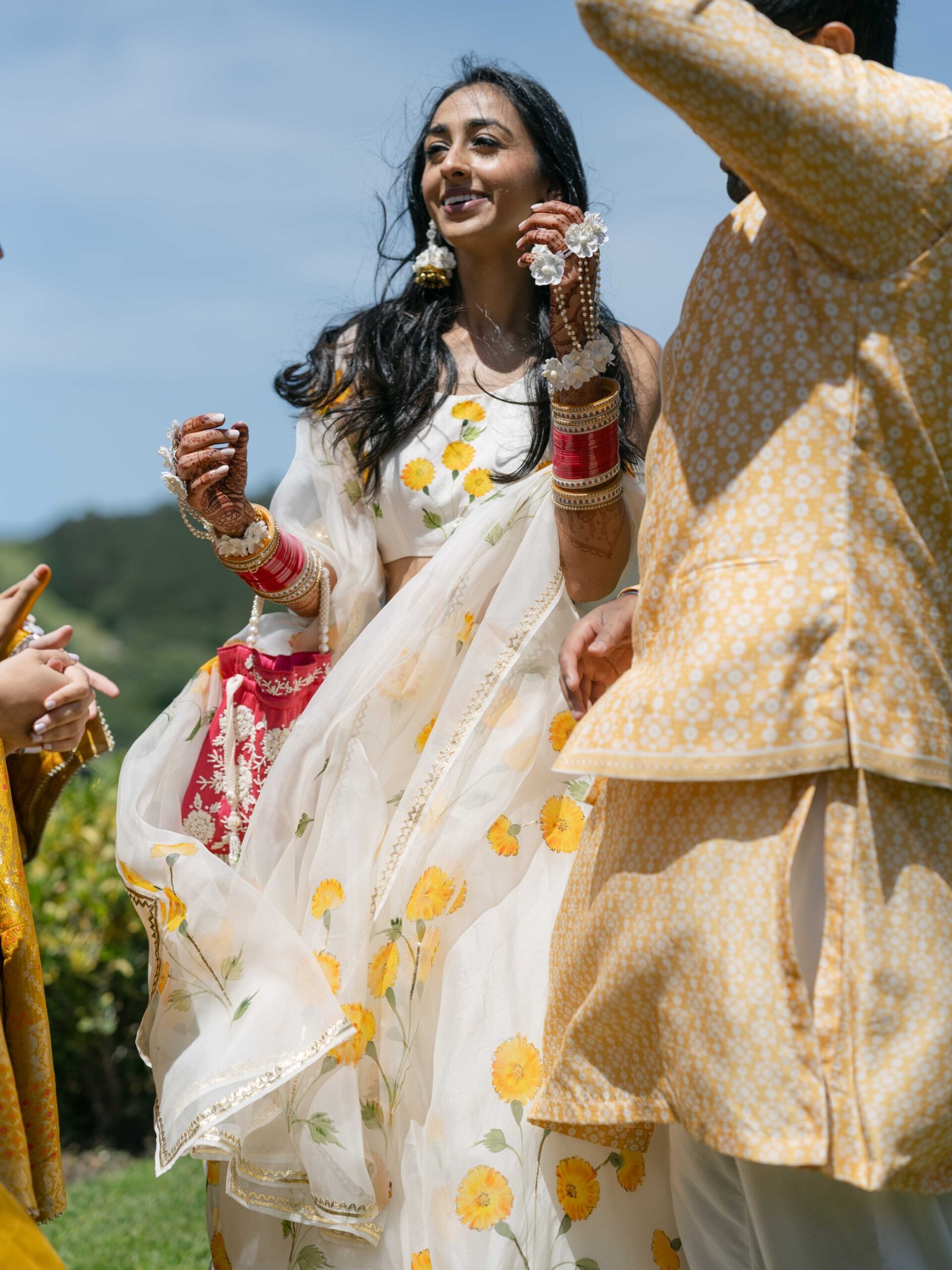 Bride in a floral lehenga laughing during the haldi ceremony in Lisbon, mehndi on her hands