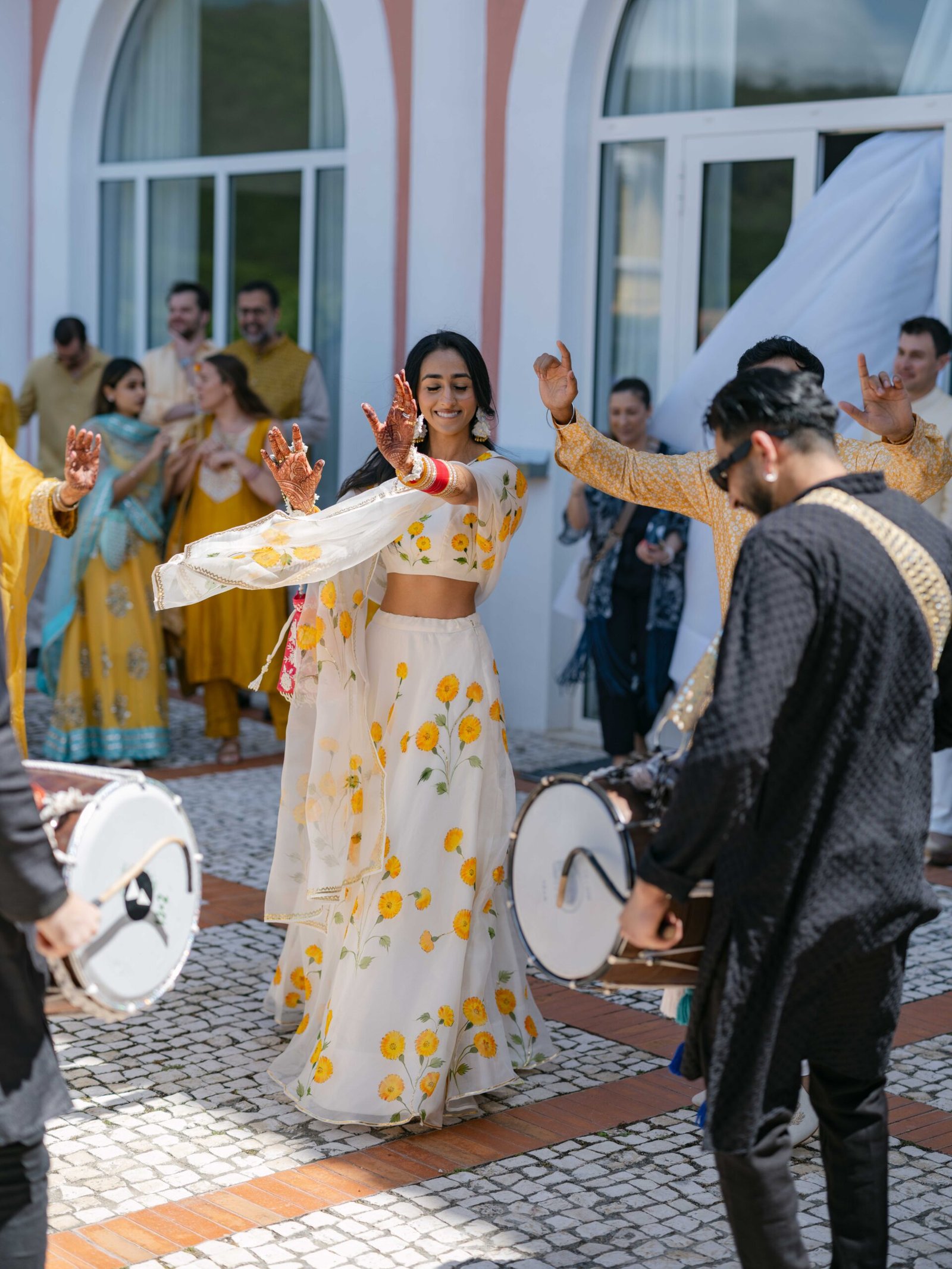 Indian bride dancing in a floral lehenga during the mehndi procession with dhol drums in Lisbon