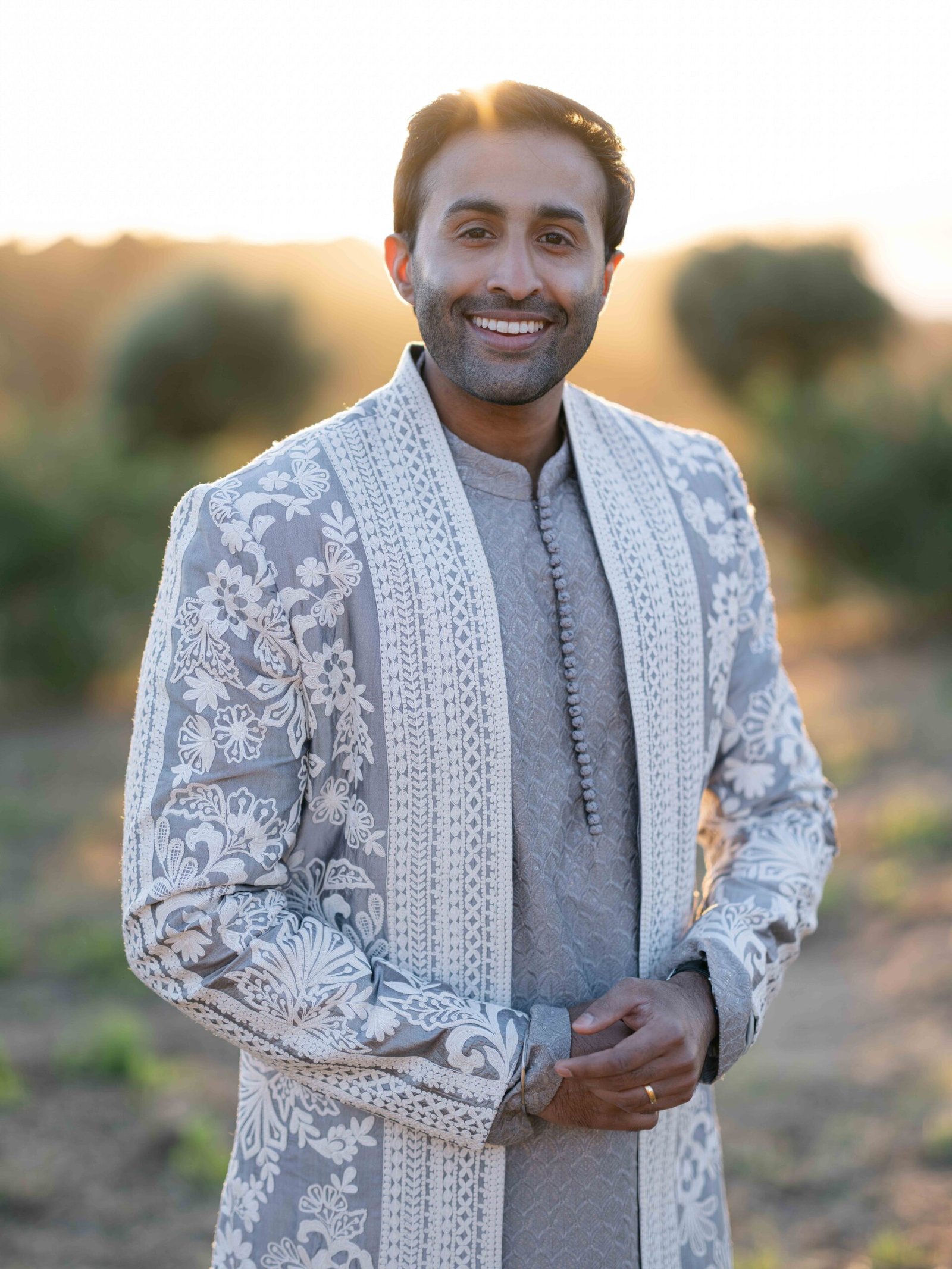 Groom in an embroidered sherwani in an olive grove near Lisbon at golden hour