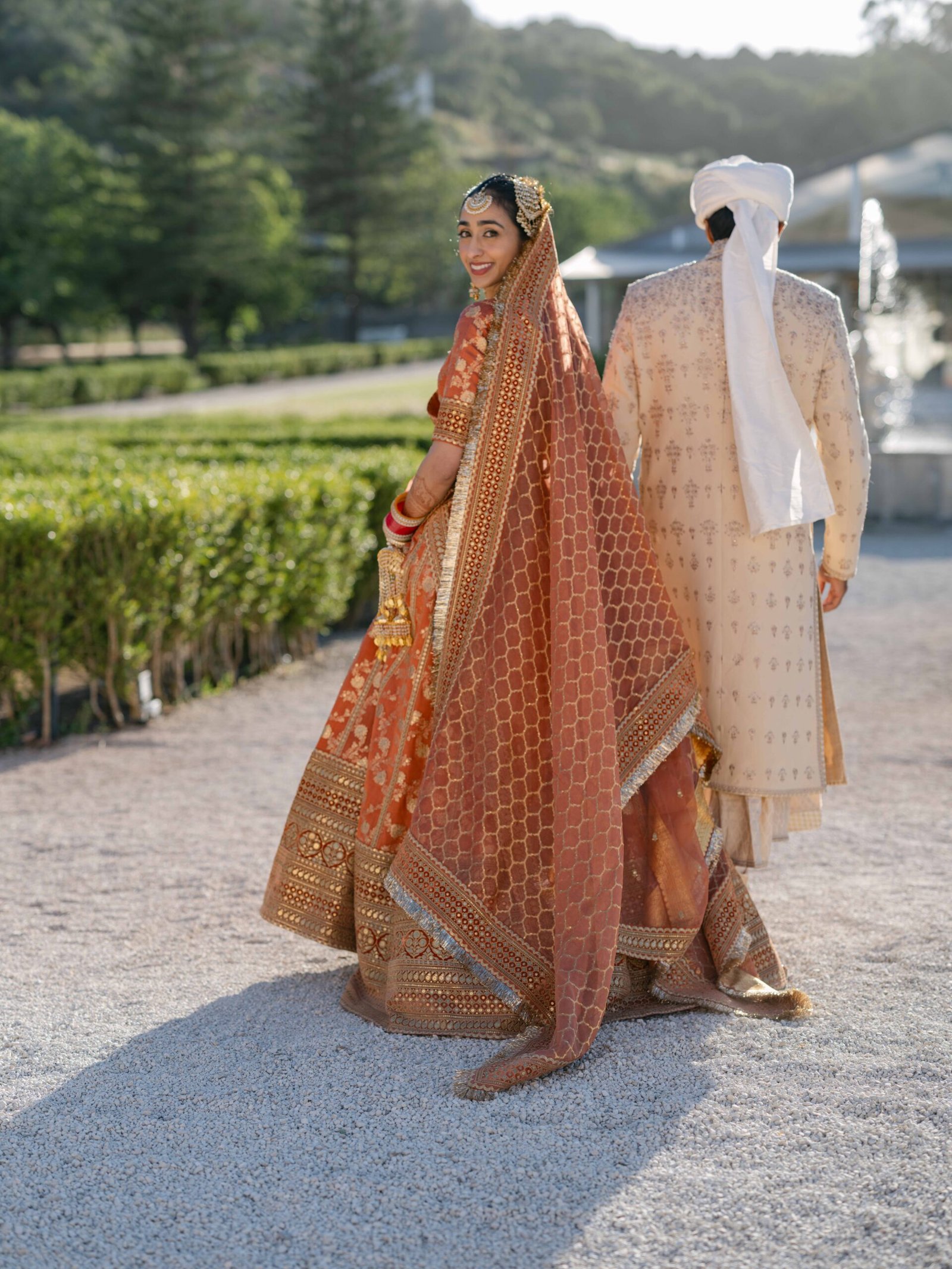 Indian bride in a rust lehenga with the groom in a garden near Lisbon at golden hour