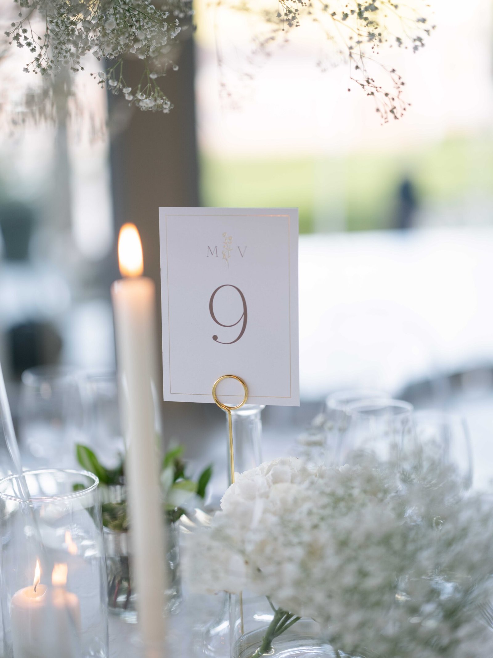 Monogrammed table number among white flowers and candlelight at a Lisbon wedding reception