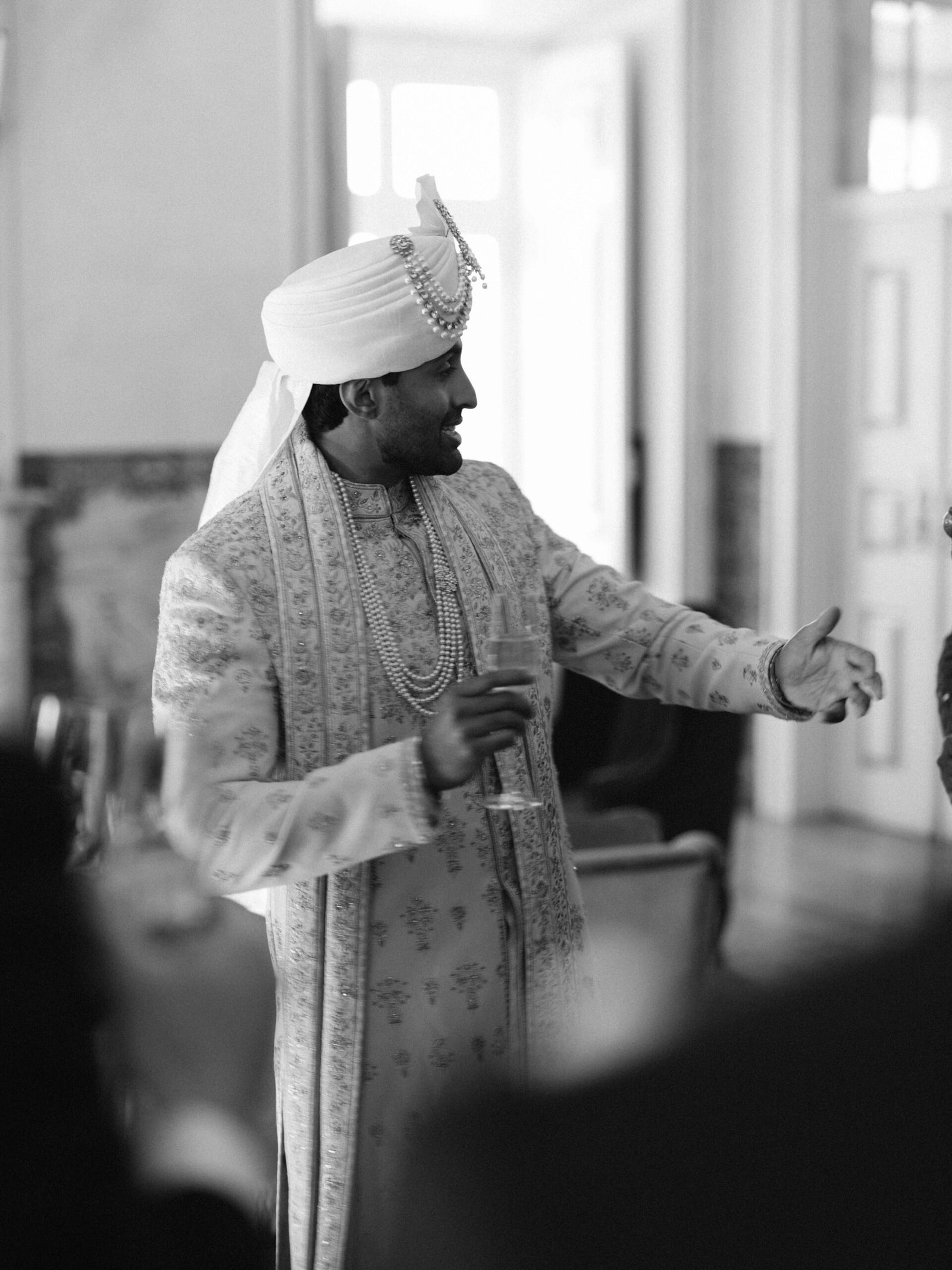 Groom in sherwani and turban raising a toast at his wedding reception in Lisbon