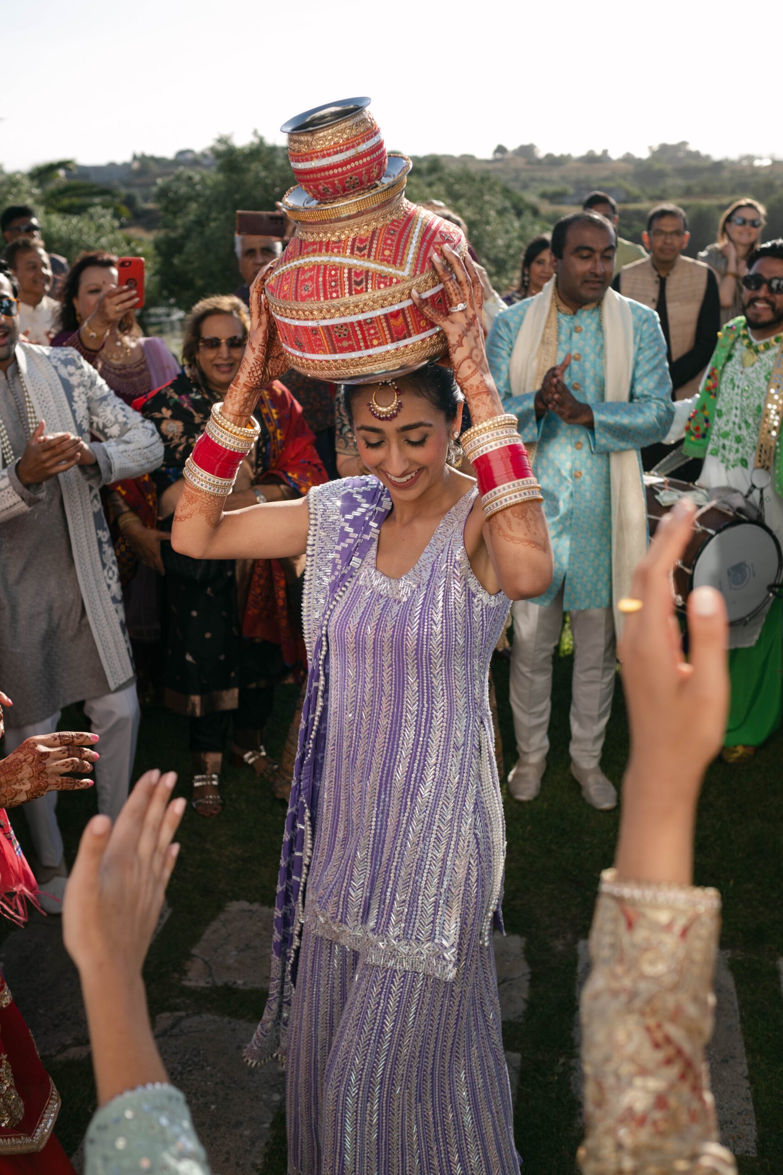 Groom lifted by guests during the baraat, the bride in a purple lehenga, Indian wedding in Lisbon