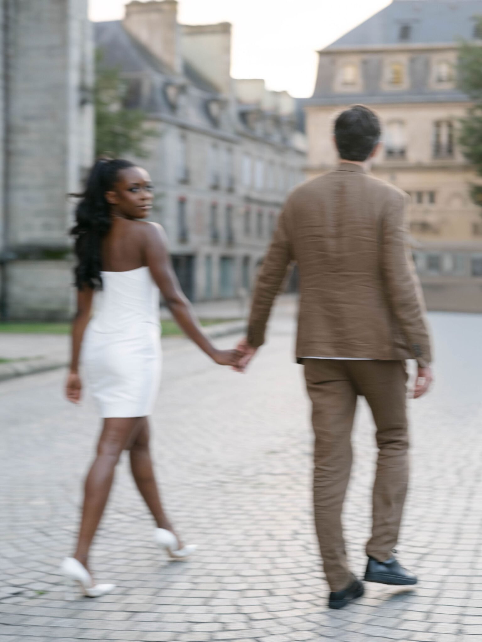 Couple walking a cobblestone square in Quimper the evening before their Orangerie de Lanniron wedding