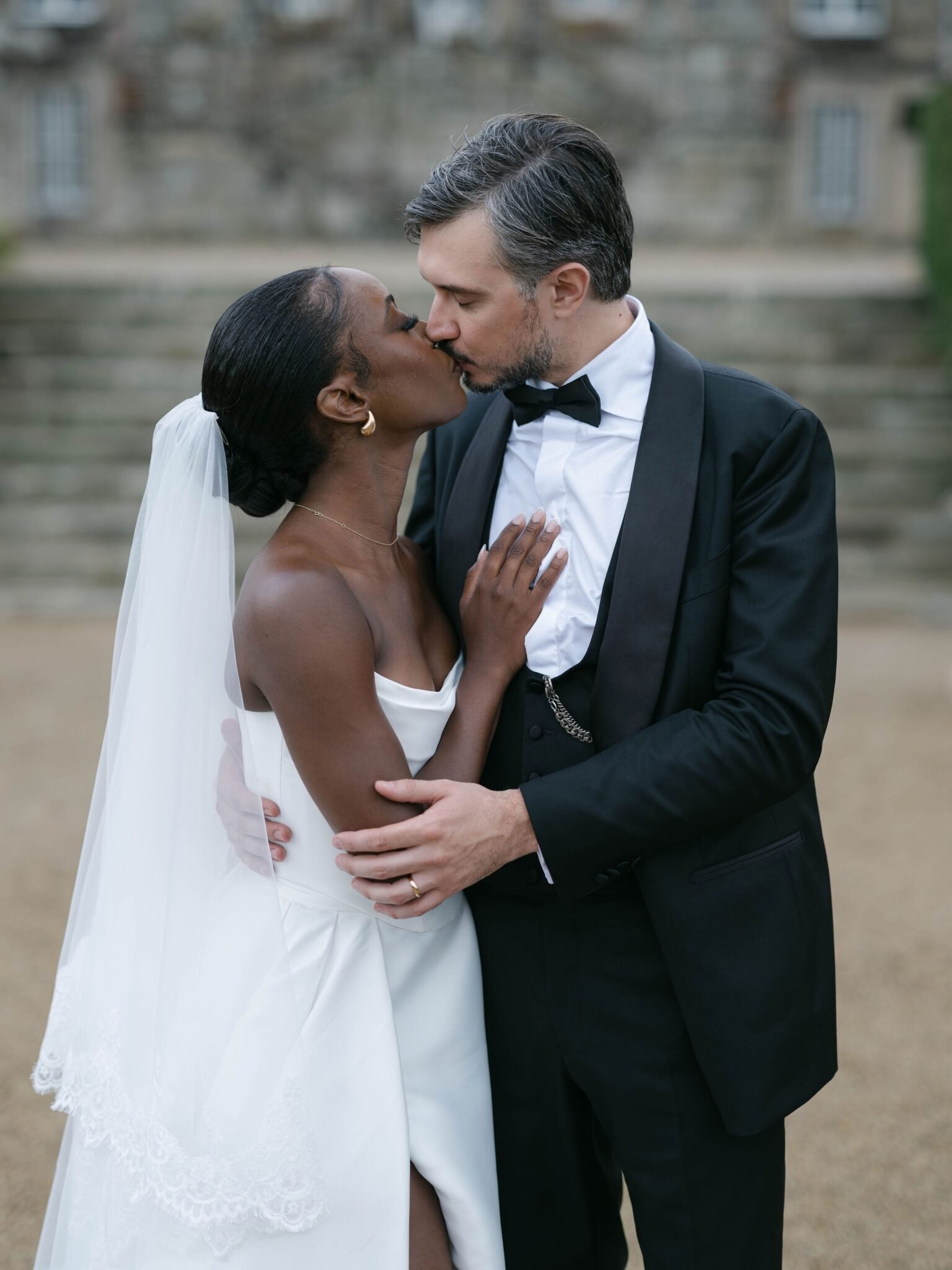 Bride and groom kissing on the chateau steps at an Orangerie de Lanniron wedding in soft evening light