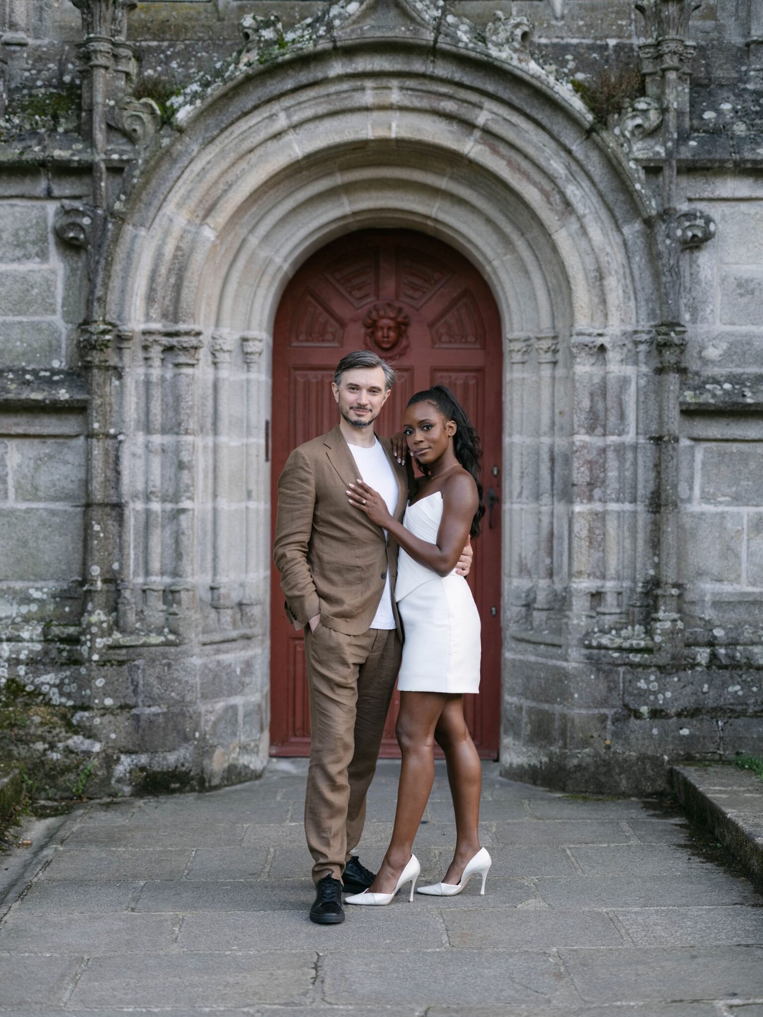 Couple photographed in a Breton chapel archway during a couple session the day before their Orangerie de Lanniron wedding