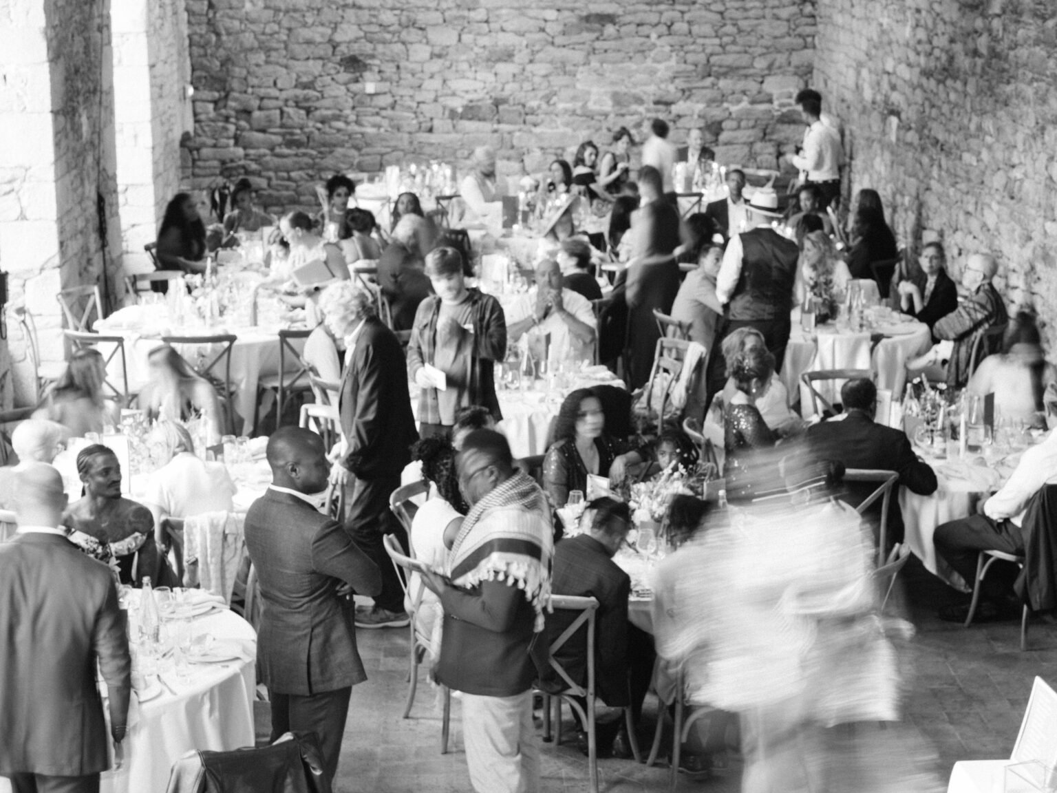 Long banquet table under stone vaults at an Orangerie de Lanniron wedding reception, black and white